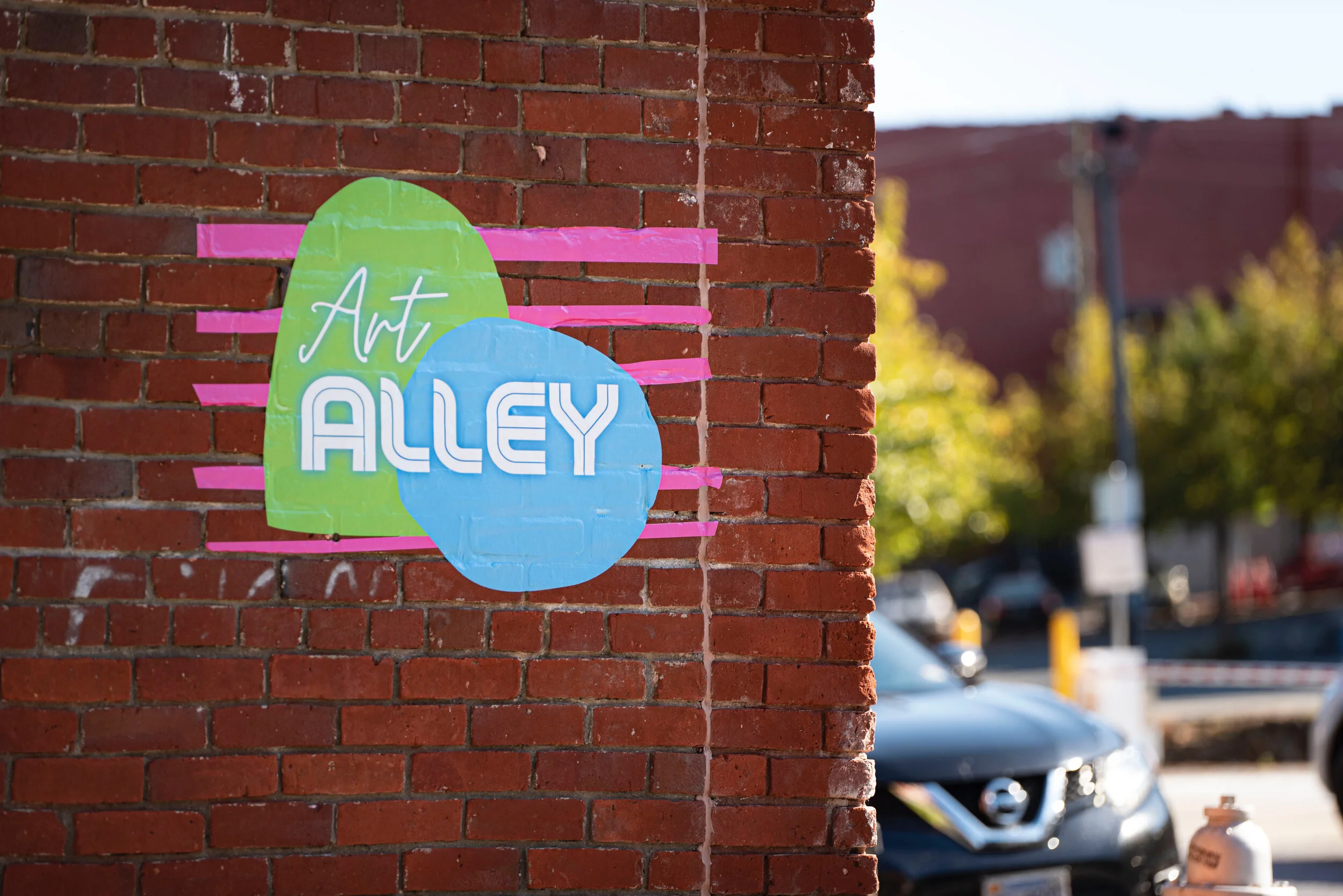 Art Alley in Downtown Lynchburg, lit with overhead lights and lined with murals