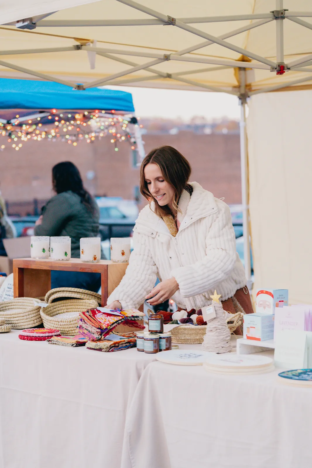 A local maker arranging her booth at the Bright Nights vendor market