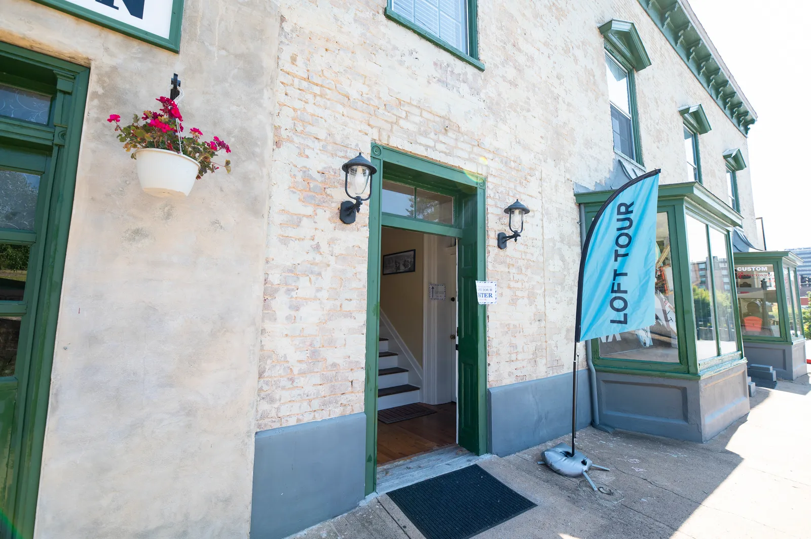 The Loft Life tour entrance, marked by a blue Loft Tour flag on a historic storefront